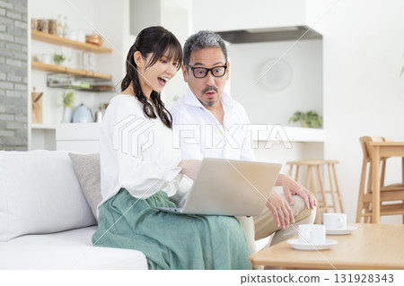 A middle-aged couple chatting while looking at a computer A middle-aged couple chatting while looking at a computer 131928343