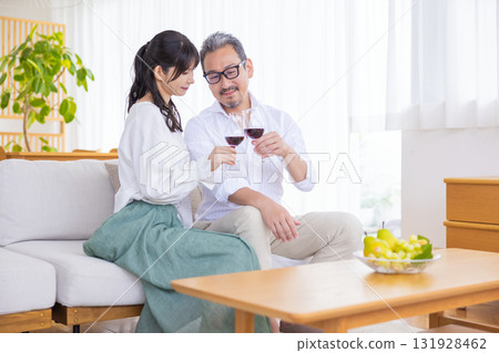 A middle-aged couple sitting on the sofa and drinking wine 131928462