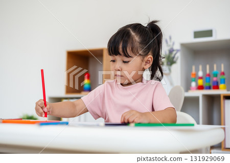 toddler baby girl training to drawing with colored pencil on desk at home 131929069