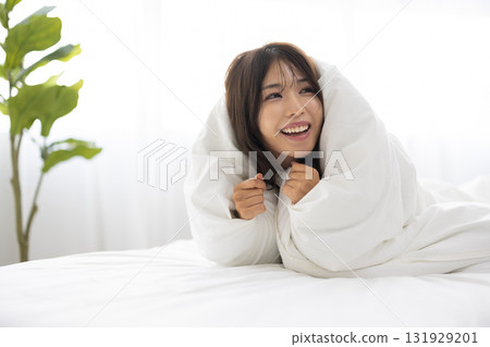 一位年輕女子在清晨的陽光下，用蒲團蓋住自己，微笑著 131929201