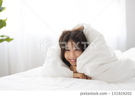 一位年輕女子在清晨的陽光下，用蒲團蓋住自己，微笑著 131929202