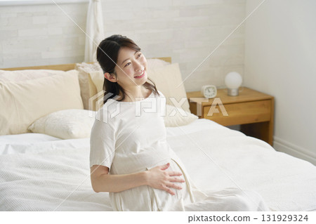 Pregnant woman sitting on bed and resting at home Pregnant woman sitting on bed and resting at home 131929324