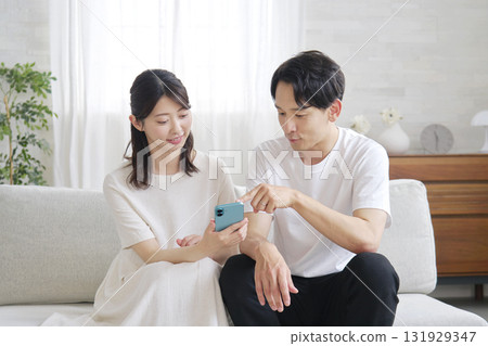 A couple using a smartphone in the living room A couple using a smartphone in the living room 131929347