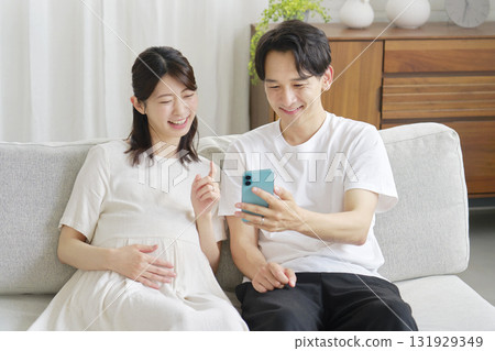 懷孕的妻子和丈夫在客廳使用智慧型手機 131929349