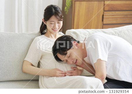 Husband putting his ear to his pregnant wife's belly Husband putting his ear to his pregnant wife's belly 131929354