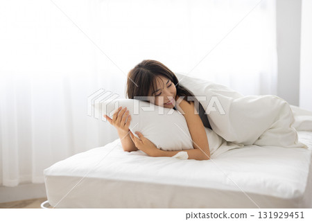 一位年輕女子在清晨的陽光下枕著枕頭睡覺 131929451