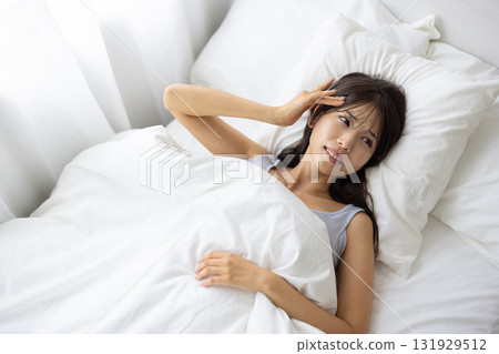 A young woman in bed with a painful expression 131929512