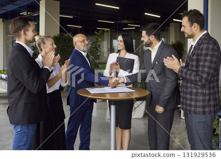 Handshake of business partners, applause of people on round table meeting in modern office Handshake of business partners, applause of people on round table meeting in modern office 131929536