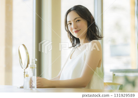 A woman looking in the mirror in the living room 131929589