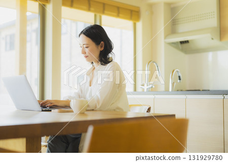 使用個人計算機的婦女在廚房裡 131929780