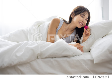 微笑的年輕女子在床上拿著心形物體 131929951