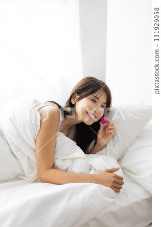 微笑的年輕女子在床上拿著心形物體 131929958
