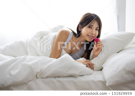 微笑的年輕女子在床上拿著心形物體 131929959
