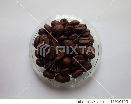 Roasted coffee beans in a small glass bowl on a white background Roasted coffee beans in a small glass bowl on a white background 131930105
