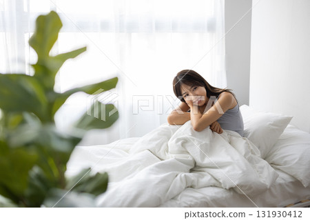 微笑的年輕女人坐在床上 131930412