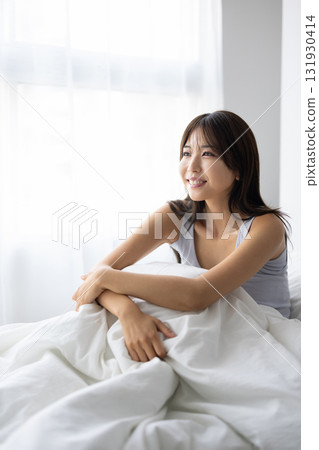 微笑的年輕女人坐在床上 131930414