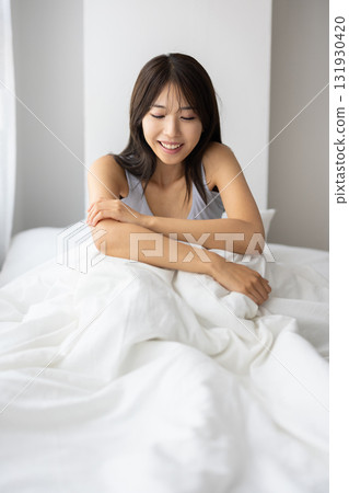 微笑的年輕女人坐在床上 131930420