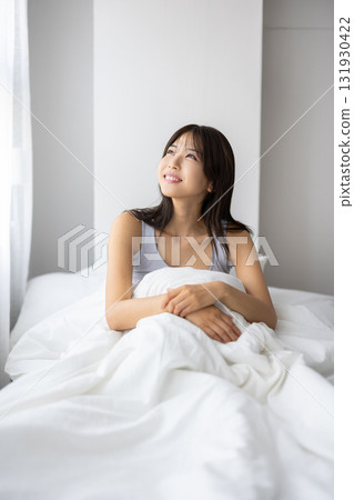 微笑的年輕女人坐在床上 131930422