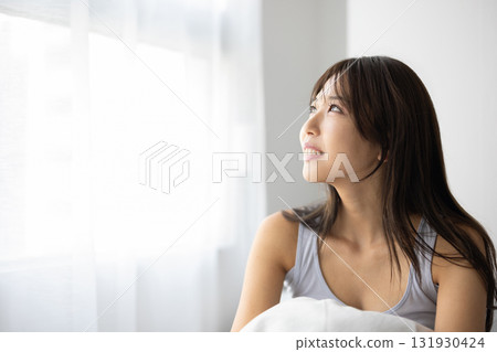 Smiling young woman sitting up in bed Smiling young woman sitting up in bed 131930424