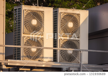 Rooftop HVAC units and ventilation systems under warm sunset light, industrial cooling and air conditioning equipment outdoors 131930689
