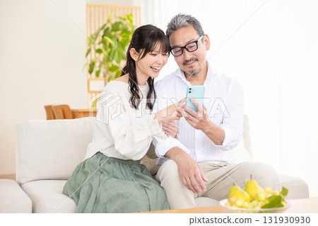 A middle-aged couple chatting while looking at a smartphone A middle-aged couple chatting while looking at a smartphone 131930930