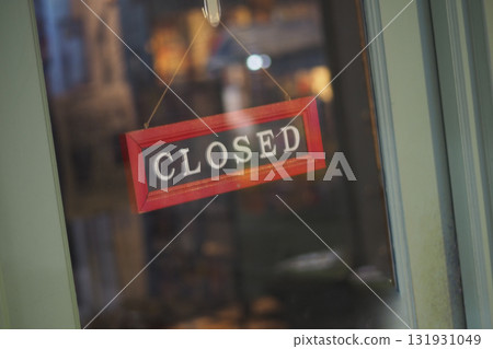 Closed sign hangs on shop door during evening hours Closed sign hangs on shop door during evening hours 131931049