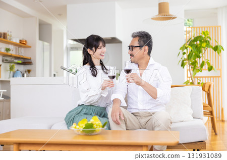 A middle-aged couple sitting on the sofa and drinking wine 131931089