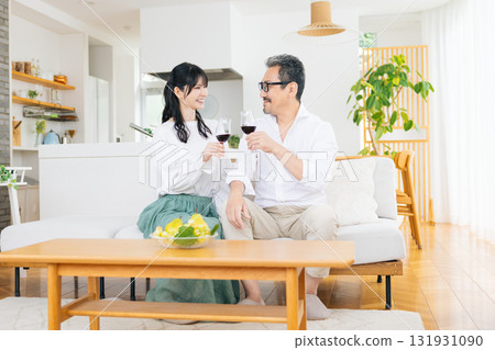 A middle-aged couple sitting on the sofa and drinking wine A middle-aged couple sitting on the sofa and drinking wine 131931090
