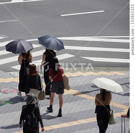 Women waiting for the traffic light at a crosswalk in a city intersection during the day 131931123