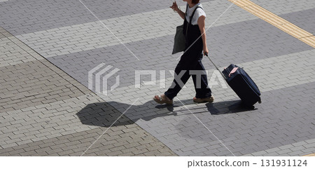 Young female tourist with a suitcase in a summer shopping street 131931124