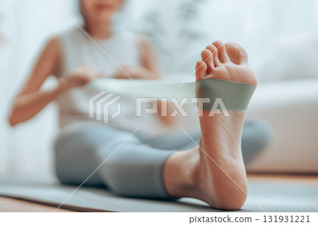 Young Asian woman doing pilates workout using elastic strap pulling with arms 131931221