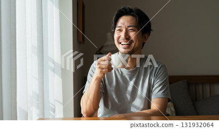 清晨陽光下，微笑的男人在窗邊享用咖啡 131932064