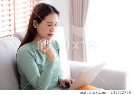 Young asian business woman working with laptop while thoughtful sitting on sofa. Young asian business woman working with laptop while thoughtful sitting on sofa. 131932709
