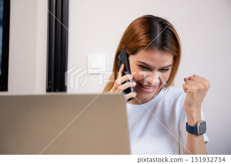 Young caucasian businesswoman talking with smartphone and working on laptop with glad. Young caucasian businesswoman talking with smartphone and working on laptop with glad. 131932734