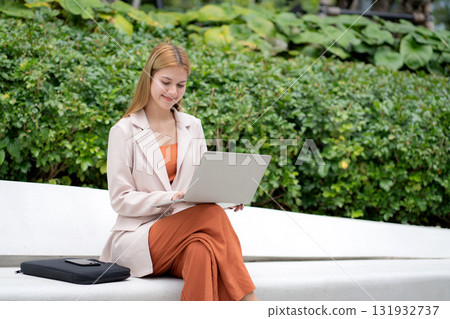 Young caucasian businesswoman working laptop sitting park, freelancer or digital nomad. 131932737