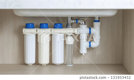Water filtration system installation under a kitchen sink with clear plumbing connections 131933432