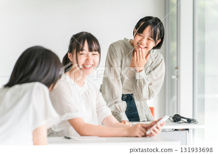 A girl in class chatting with a smile while using her smartphone in a classroom at school A girl in class chatting with a smile while using her smartphone in a classroom at school 131933698