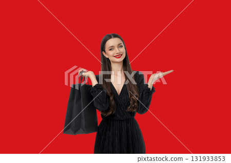 Woman with long hair in black dress holding shopping bag 131933853