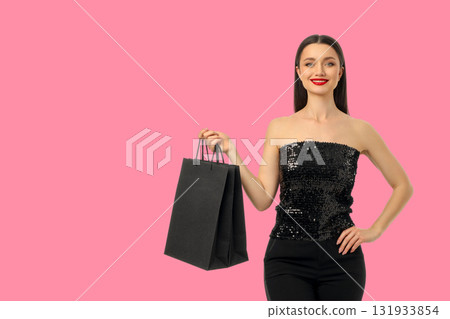 Woman poses confidently holding a black shopping bag 131933854