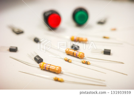 Electronic components on white background with red and green push buttons, resistors and transistors for DIY electronics and engineering education. Electronic components on white background with red and green push buttons, resistors and transistors for DIY electronics and engineering education. 131933939