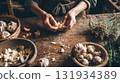 Hands breaking a head of garlic on a rustic wooden table with herbs, organic cooking preparation 131934389