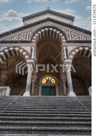 The Amalfi Cathedral in Italy features Romanesque, Byzantine, and Gothic styles, with striped arches, geometric patterns, and golden mosaics above the entrance. 131934678