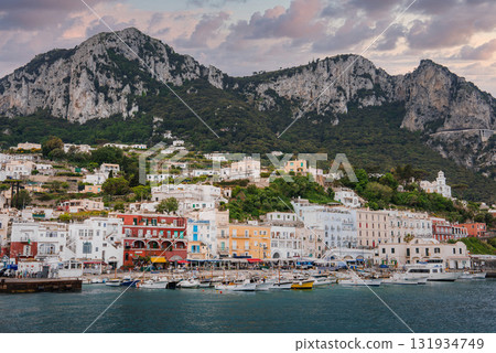 Colorful buildings line the Marina Grande waterfront on Capri, Italy, with boats in the harbor, limestone cliffs, lush greenery, and a hillside church. Colorful buildings line the Marina Grande waterfront on Capri, Italy, with boats in the harbor, limestone cliffs, lush greenery, and a hillside church. 131934749