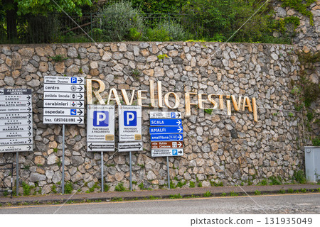 A stone wall in Ravello, Italy, displays the golden words 'Ravello Festival' above directional signs to Piazza Duomo, Scala, Amalfi, and parking areas. A stone wall in Ravello, Italy, displays the golden words 'Ravello Festival' above directional signs to Piazza Duomo, Scala, Amalfi, and parking areas. 131935049