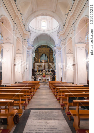 The church interior features high vaulted ceilings, ornate columns, a golden altar with a crucifix, a pipe organ, wooden pews, and stone floor inscriptions. 131935231