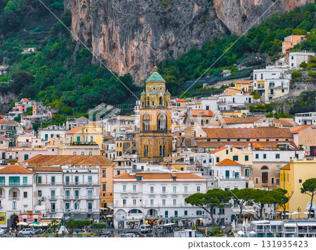 Amalfi town on Italy's Amalfi Coast features the Cathedral of St. Andrew, colorful buildings, steep cliffs, and a lively waterfront with people and vehicles. Amalfi town on Italy's Amalfi Coast features the Cathedral of St. Andrew, colorful buildings, steep cliffs, and a lively waterfront with people and vehicles. 131935423
