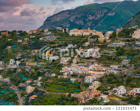 Aerial view of Ravello, Italy, featuring terraced hills, Mediterranean style buildings, villas, churches, gardens, olive groves, and rugged mountains. Aerial view of Ravello, Italy, featuring terraced hills, Mediterranean style buildings, villas, churches, gardens, olive groves, and rugged mountains. 131935471