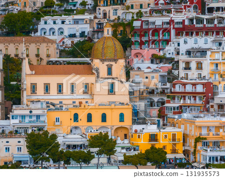 View of Positano, Italy, featuring pastel colored buildings on a steep hillside and the Church of Santa Maria Assunta with its tiled dome. View of Positano, Italy, featuring pastel colored buildings on a steep hillside and the Church of Santa Maria Assunta with its tiled dome. 131935573