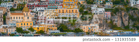 Positano, Italy, features vibrant buildings on a steep cliff, a central dome of the Church of Santa Maria Assunta, and a beach with umbrellas below. Positano, Italy, features vibrant buildings on a steep cliff, a central dome of the Church of Santa Maria Assunta, and a beach with umbrellas below. 131935589
