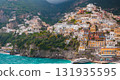 View of Positano's vibrant hillside buildings, turquoise Tyrrhenian Sea, docked yacht, small beach, lush greenery, and rugged coastal cliffs. 131935595